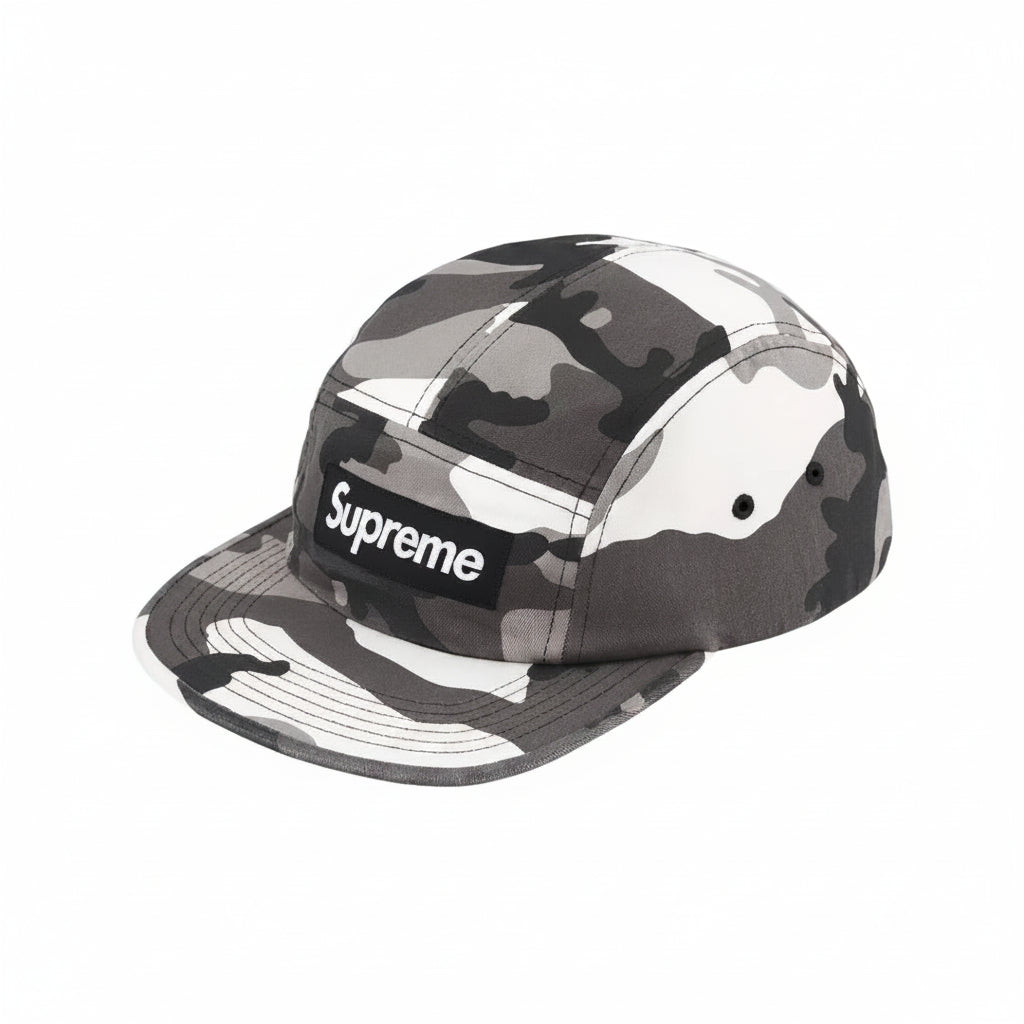 A Supreme 5-panel camp cap in a gray, black, and white camouflage pattern, featuring the classic black box logo with white text on the front.