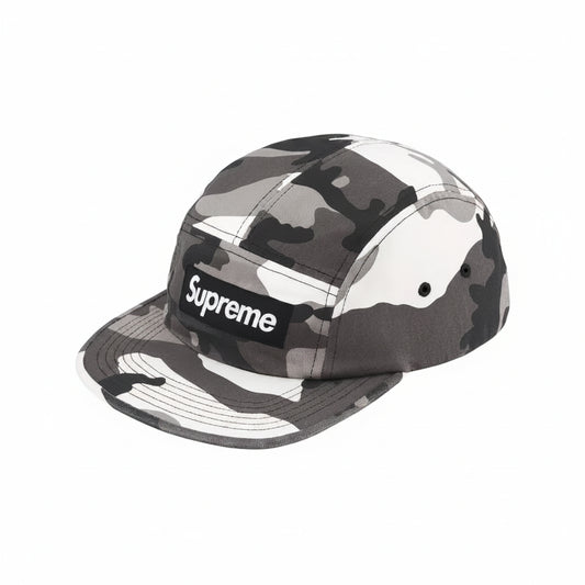 A Supreme 5-panel camp cap in a gray, black, and white camouflage pattern, featuring the classic black box logo with white text on the front.